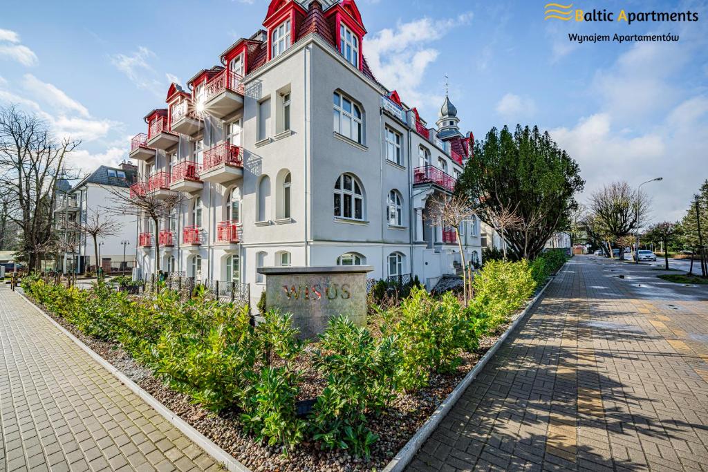 um grande edifício branco com um telhado vermelho em Baltic Apartments - Wisus em Świnoujście