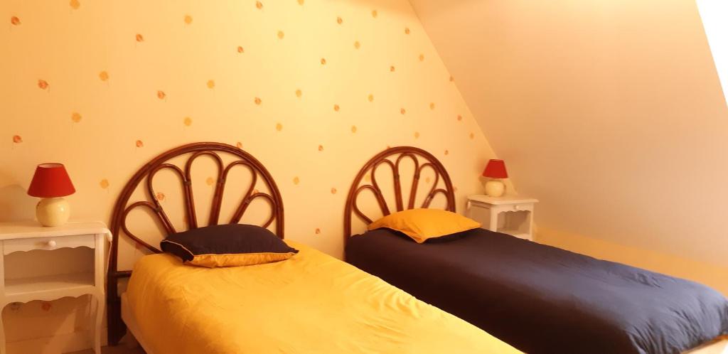 two beds sitting next to each other in a bedroom at Gite de Kervao, Camélias, proche mer (800 mètres), meublé tourisme 3 étoiles in Ploudalmézeau