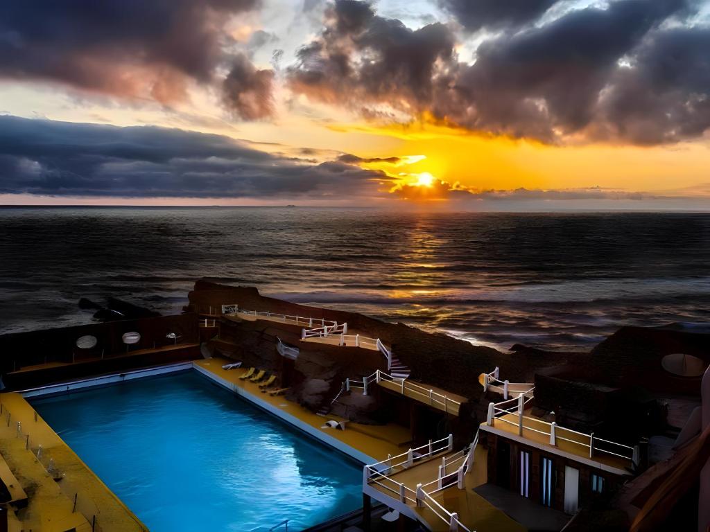 a pool on a cruise ship with a sunset at Habitaciones con vistas a playa Do Guincho in Cascais
