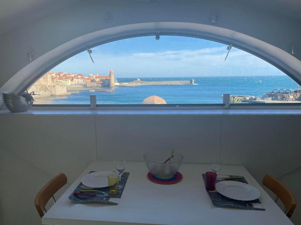 a table with two plates and a view of the ocean at 3CONV48- Charmant T2 avec vue imprenable en face plage Collioure in Collioure