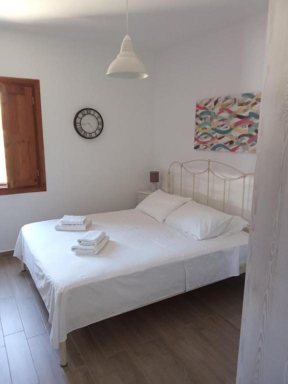 a white bed in a bedroom with a clock on the wall at kominoshouses in Skala