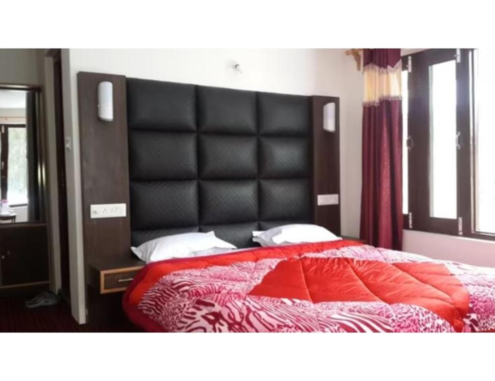 a bedroom with a large bed with a black headboard at Hotel Grand Abdullah, Pahalgam in Pahalgām