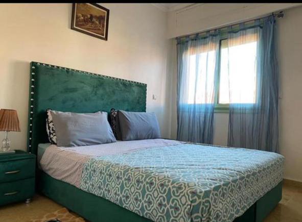 a bedroom with a bed with a green headboard and a window at appartement au coeur de rabat in Rabat