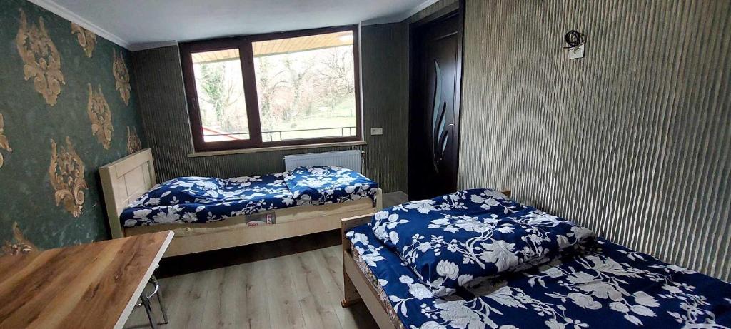 een kamer met 2 bedden, een tafel en een raam bij Guest House Godogani in Godogani