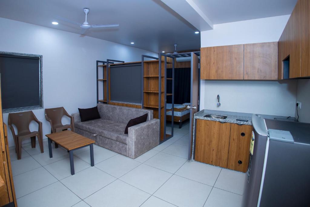 uma cozinha e sala de estar com um sofá e uma mesa em 24 CARAT STUDIO APARTMENTS em Porbandar
