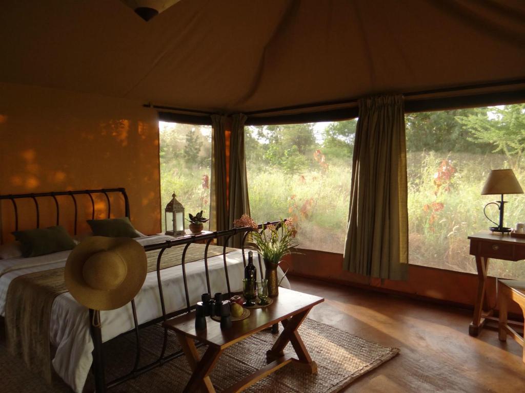 a bedroom with a bed and a large window at Ikweta Safari Camp in Maua