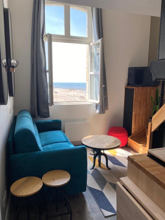 a living room with a blue couch and a table at Une fenêtre sur l océan, Studio duplex dans résidence de standing avec piscine et vue sur mer in Le Croisic