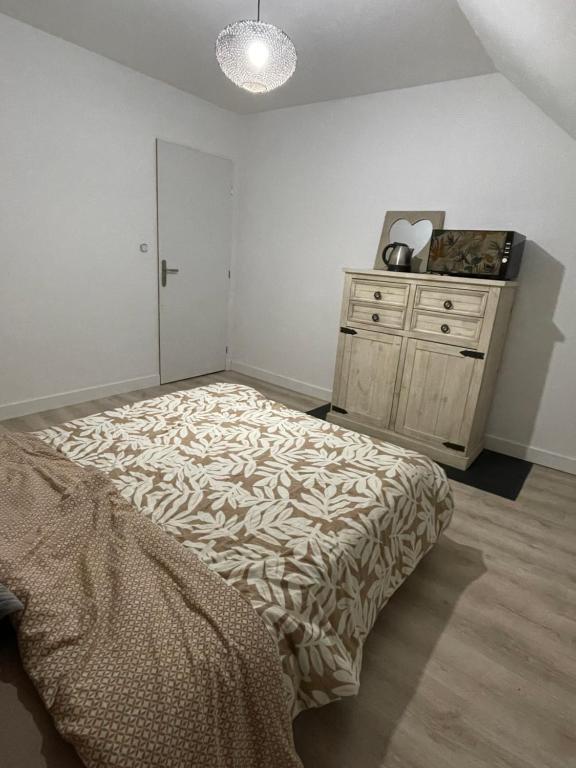 a bedroom with a bed and a dresser in it at La chambre de la tanière in Muzillac