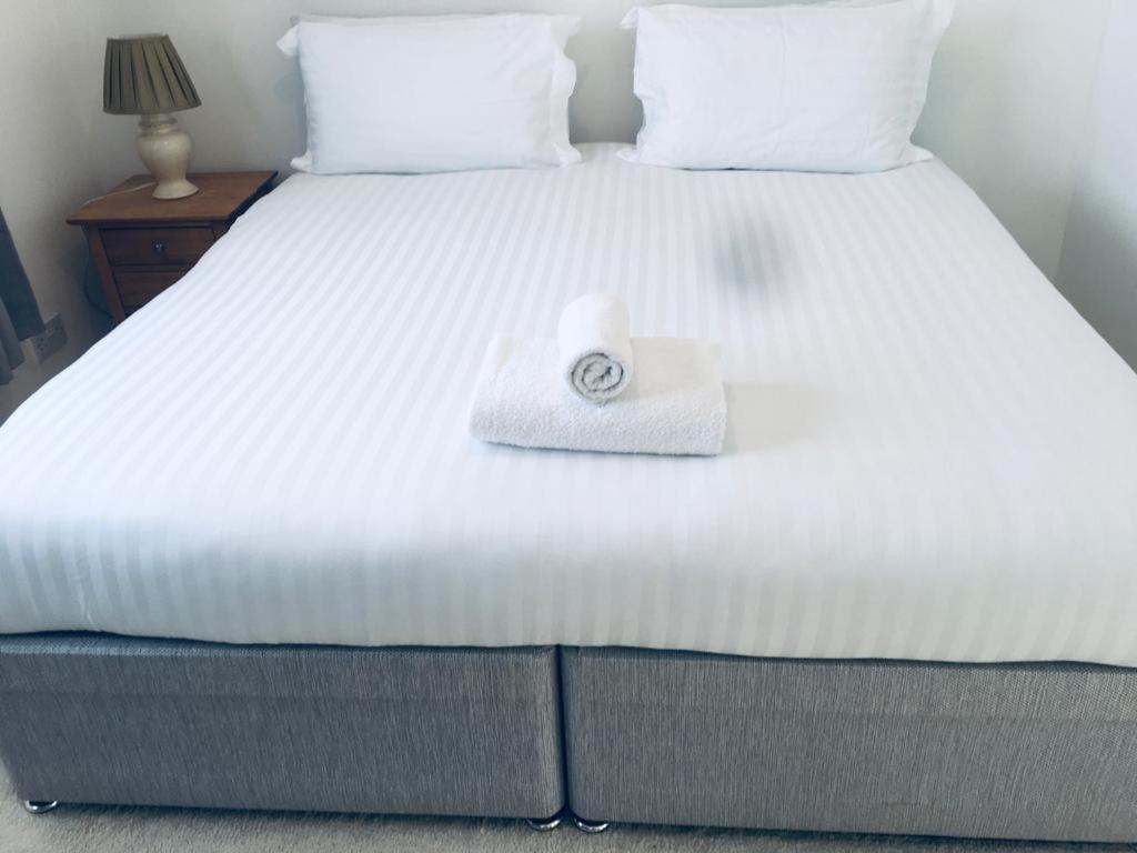 a white bed with a rolled up towel on it at Jessjoe in Bournemouth