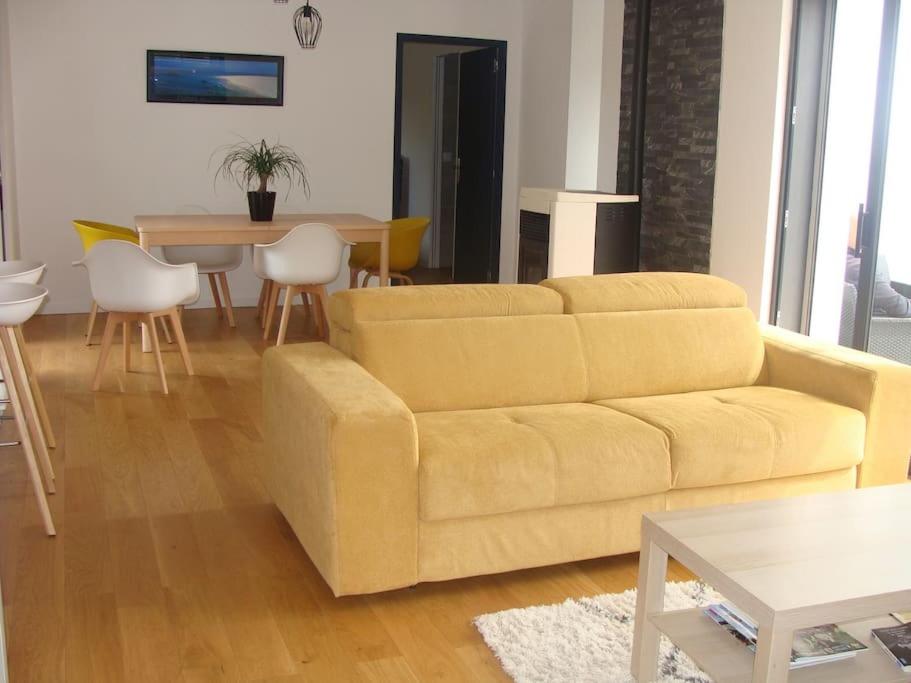ein Wohnzimmer mit einem gelben Sofa und einem Tisch in der Unterkunft Maison moderne pour 4- 5 personnes in Sulniac