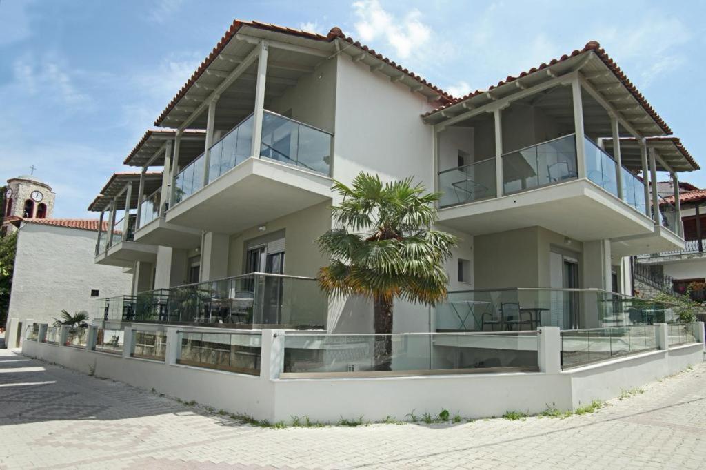 a white building with a palm tree in front of it at EL MARE ROOMS in Pefkohori