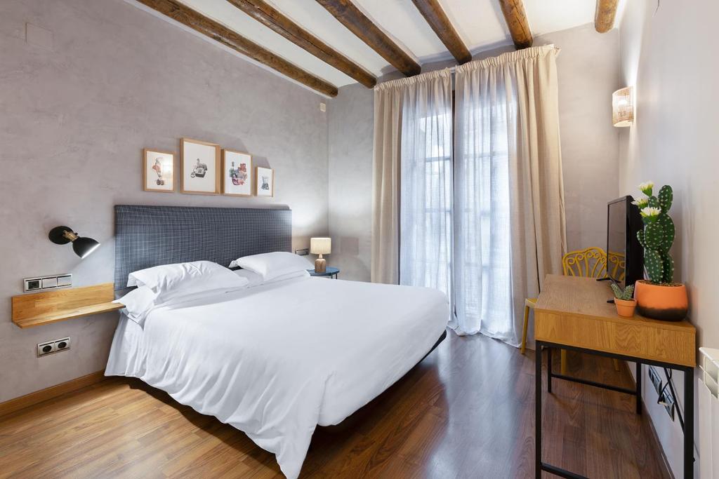 Un dormitorio con una gran cama blanca y una ventana en Hostal Pichorradicas en Tudela