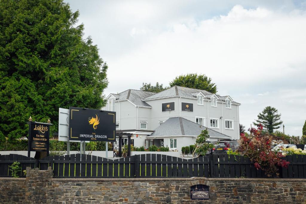 una casa blanca con un cartel delante en The Imperial Dragon Hotel en Saundersfoot