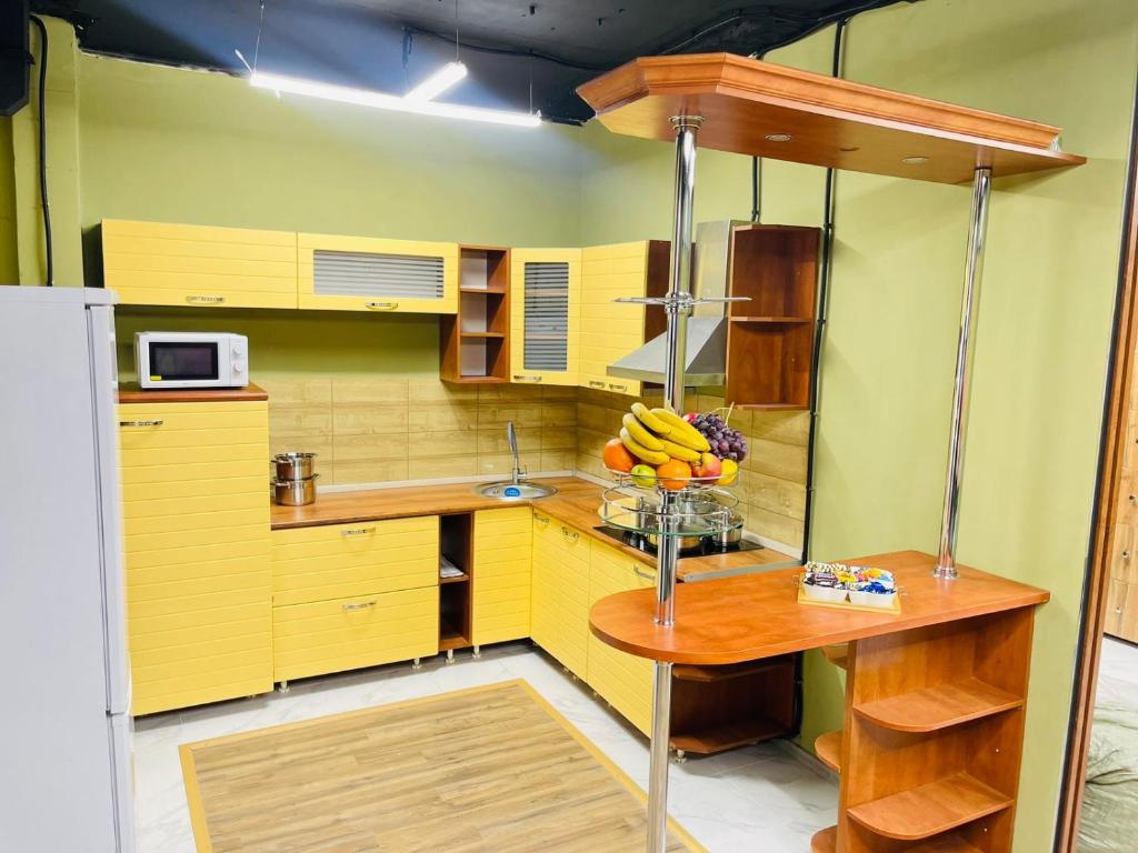 a kitchen with yellow cabinets and a bowl of fruit on a table at KOCHEVNIK HOSTEL in Almaty