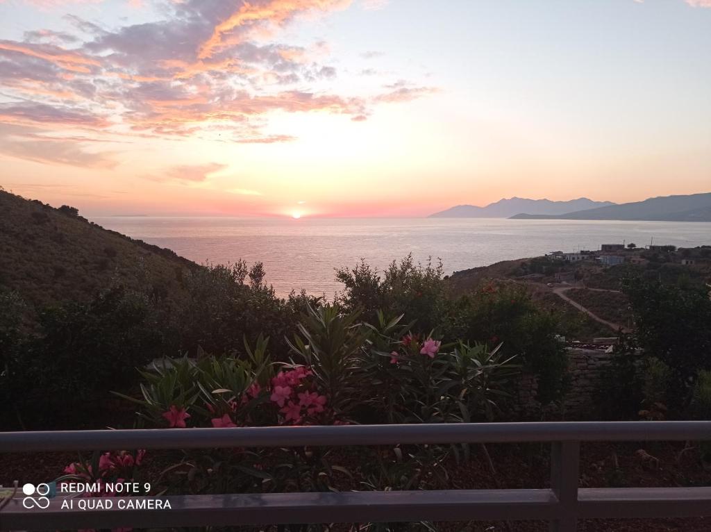 uma vista para o oceano ao pôr-do-sol a partir de uma varanda em Amar Seaside em Ksamil