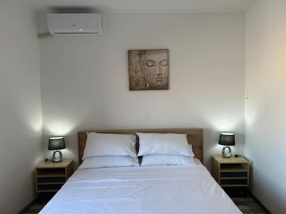 um quarto com uma cama com duas mesas de cabeceira e um quadro na parede em Μοντέρνο σπίτι κοντά στον κέντρο της Πόλης! em Mitilene