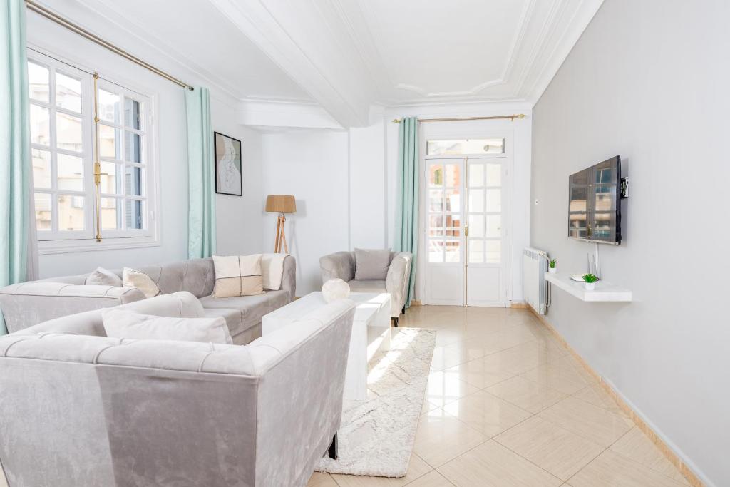 a white living room with couches and a tv at Appartement Luxueux à Hydra in Hydra