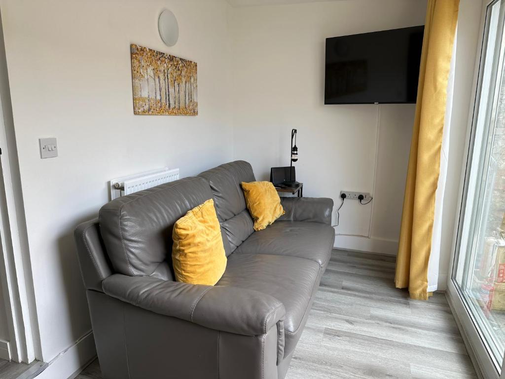 a leather couch with two yellow pillows in a living room at Carmen Sylva Llandudno Beach ground floor Flat in Llandudno