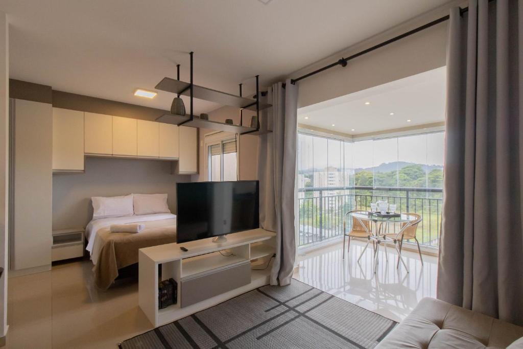 a bedroom with a bed and a tv and a balcony at 0814 - Simplicidade e Praticidade in Guarulhos