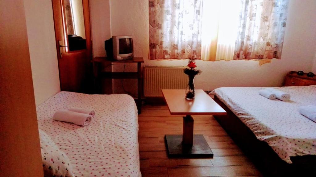 a room with two beds and a table and a tv at Hotel Markovi Kuli TD in Prilep