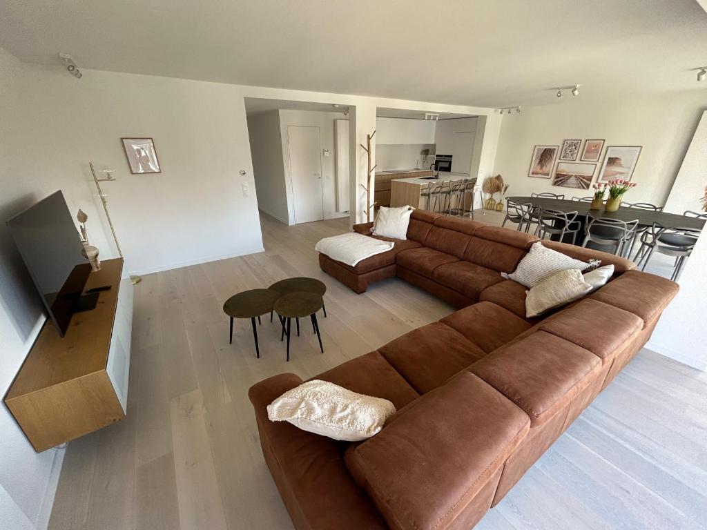 a living room with a brown couch and a kitchen at ASTRID 0301 - App voor 6 personen in De Panne