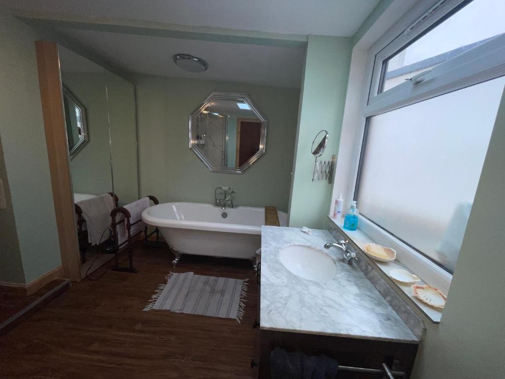 W łazience znajduje się wanna, umywalka i lustro. w obiekcie Lovely double room in very good area w Edynburgu