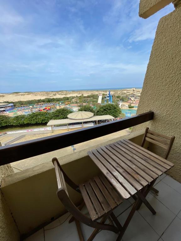 um banco de madeira sentado em cima de uma varanda com vista em Réf 392 Seignosse océan , appartement VUE MER, proximité immédiate de la plage Idéal famille 4 personnes em Seignosse