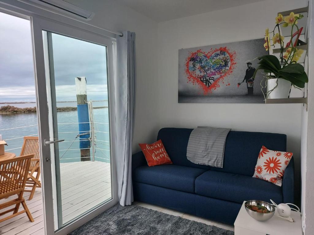 un divano blu in soggiorno con porta scorrevole in vetro di Floating House Anfora a Grado
