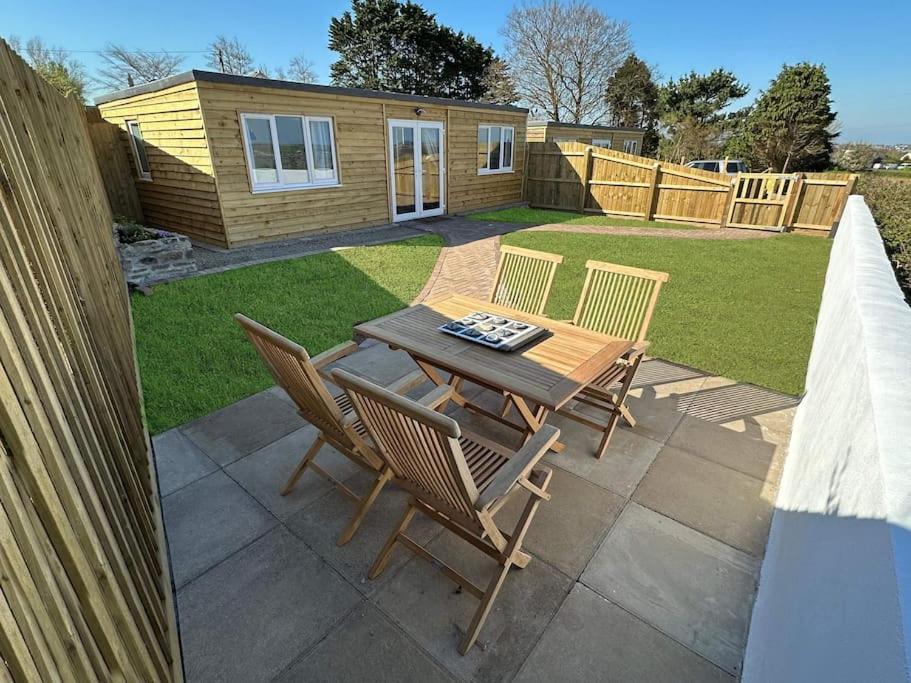 a patio with a table and chairs in a yard at Citrus Chalet, modern light and airy! in Redruth