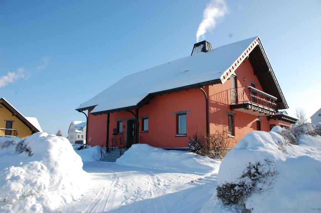 una casa rossa ricoperta di neve con la neve accumulata di Gemütliche Ferienwohnung im schönen Erzgebirge - Wohnung Frühling a Eibenstock