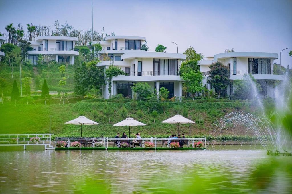 un grupo de personas sentadas bajo sombrillas cerca de un estanque en Ivory Villas Hòa Bình, en Hòa Bình