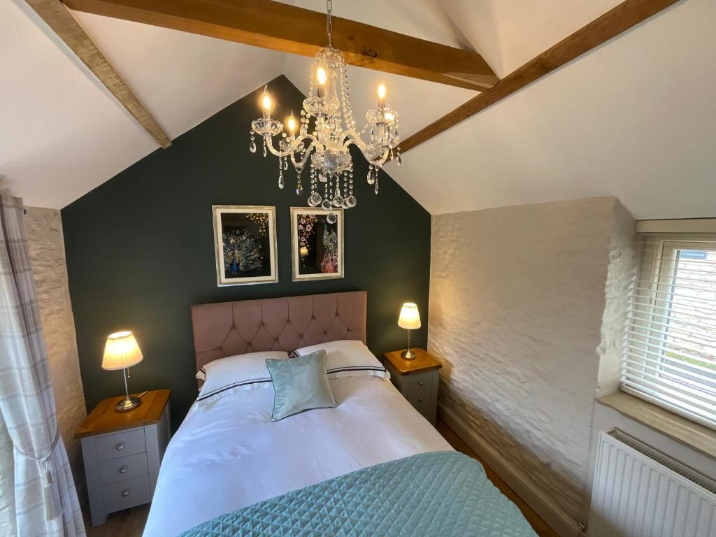 a bedroom with a large bed and a chandelier at Luxury Barn near Stamford in Wansford