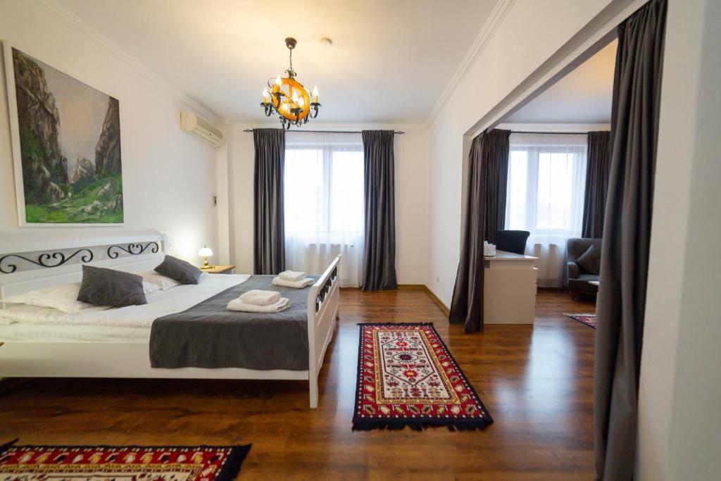 1 dormitorio con cama blanca y lámpara de araña en Pensiunea Koronka, en Corunca