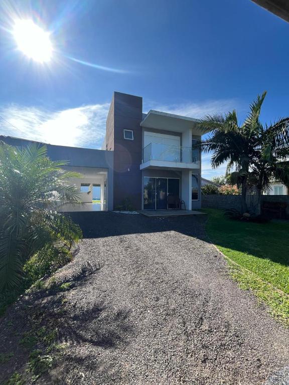 una casa con una entrada de grava delante de ella en Casa com piscina en Capão da Canoa