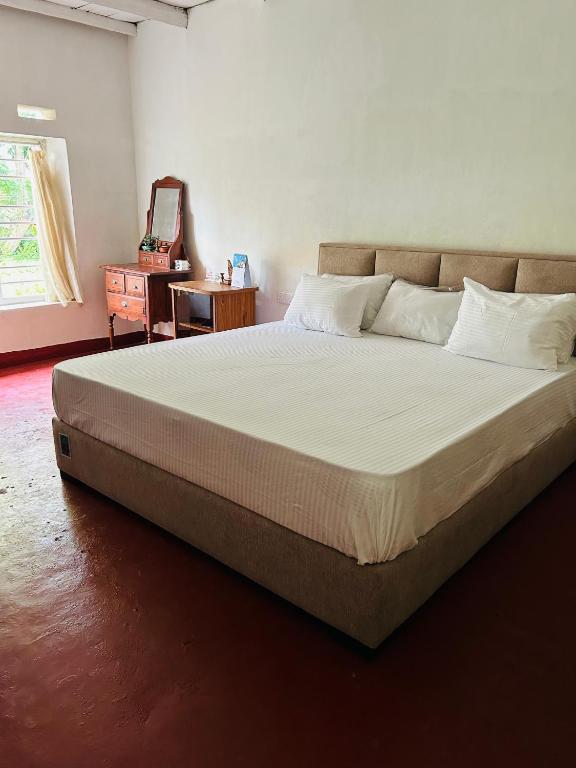 a bedroom with a large bed with white sheets at The Eco-Lodge in Habaraduwa