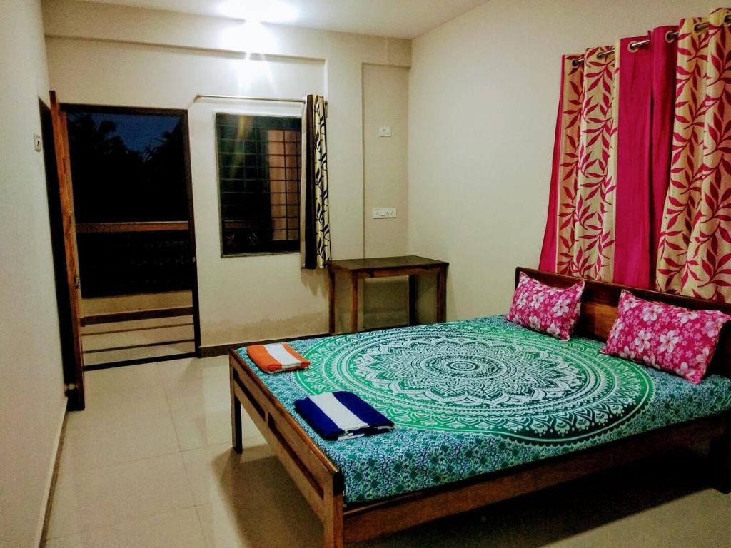 ein Schlafzimmer mit einem Bett mit einer grünen und blauen Tagesdecke in der Unterkunft RN GUEST HOUSE ARAMBOL GOA in Arambol