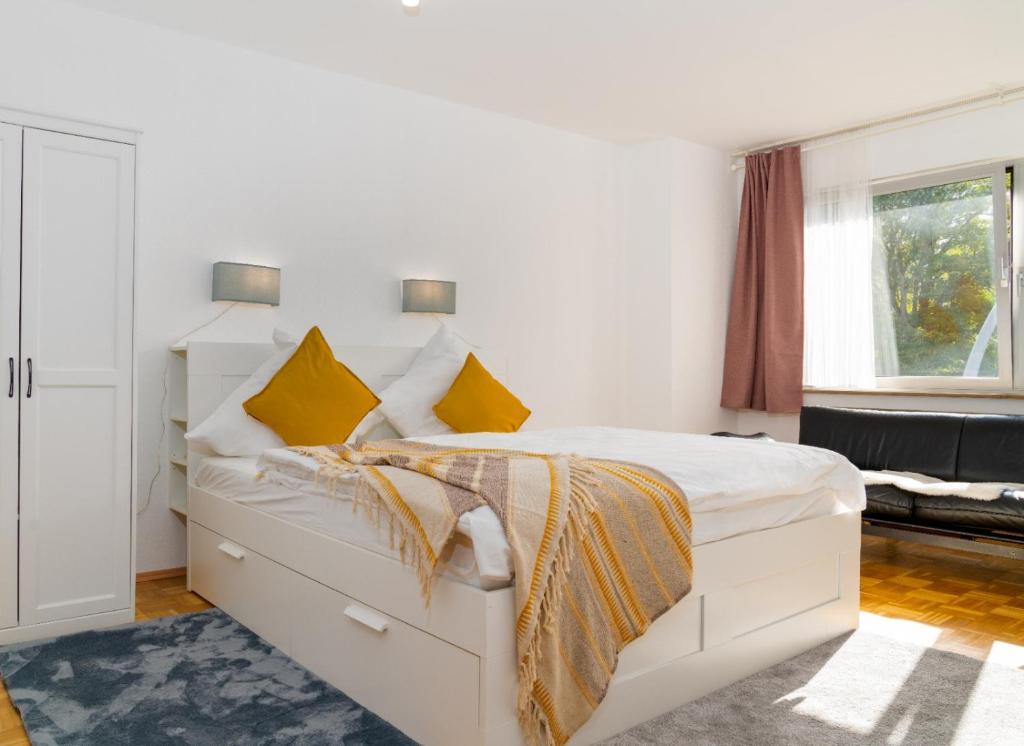1 dormitorio blanco con 1 cama blanca grande con almohadas amarillas en Gemütliche Wohnung - Rüttenscheid, en Essen