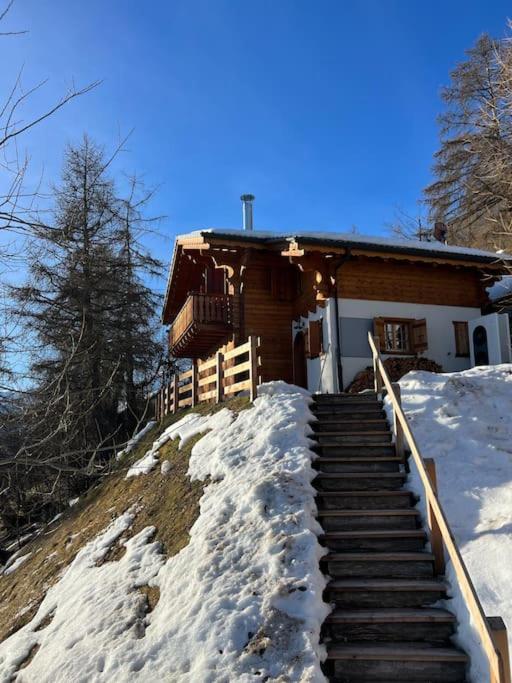 ein Haus mit Treppen im Schnee davor in der Unterkunft Chalet Stickie by Swiss Alps Village in Hérémence