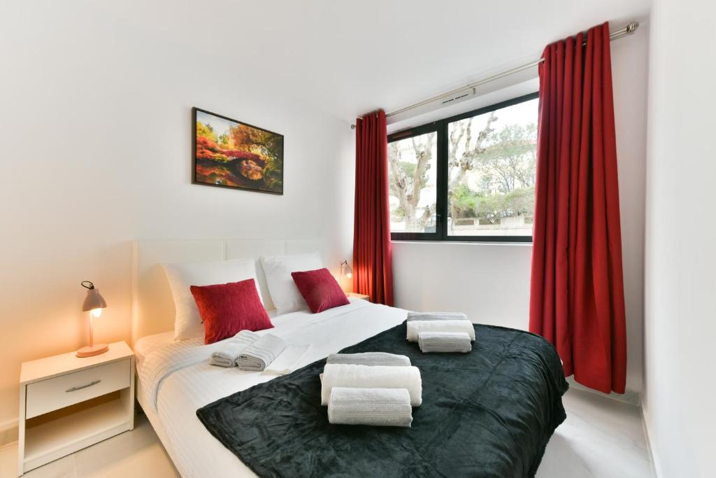 a bedroom with a large bed with red curtains at Le Coquillage - 200 mètres de la Plage in Cannes