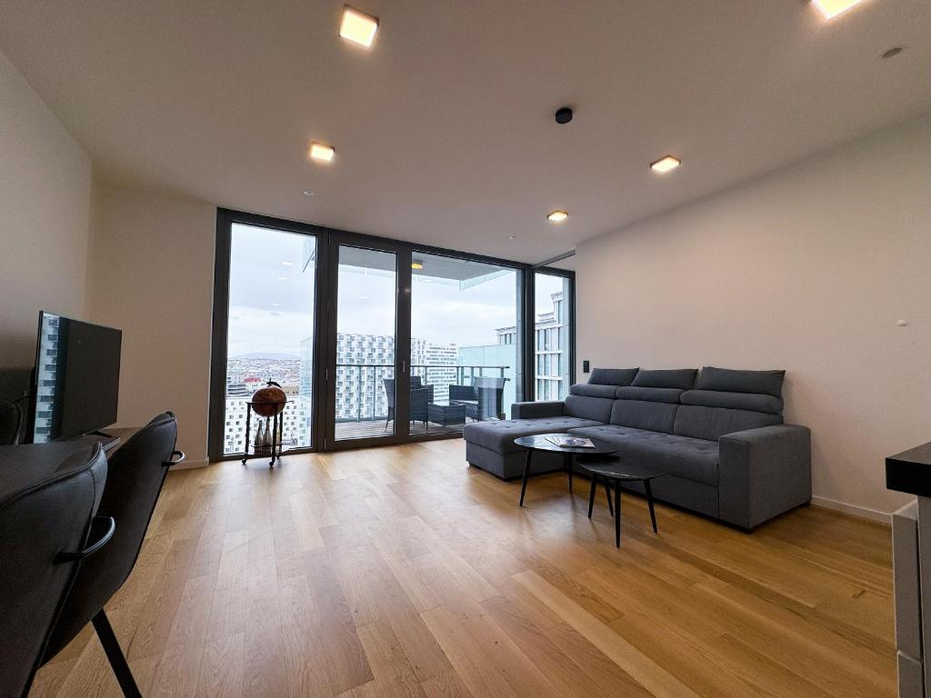 ein Wohnzimmer mit einem Sofa und einem großen Fenster in der Unterkunft LUXUS-Apartment mit Weitblick in Wien