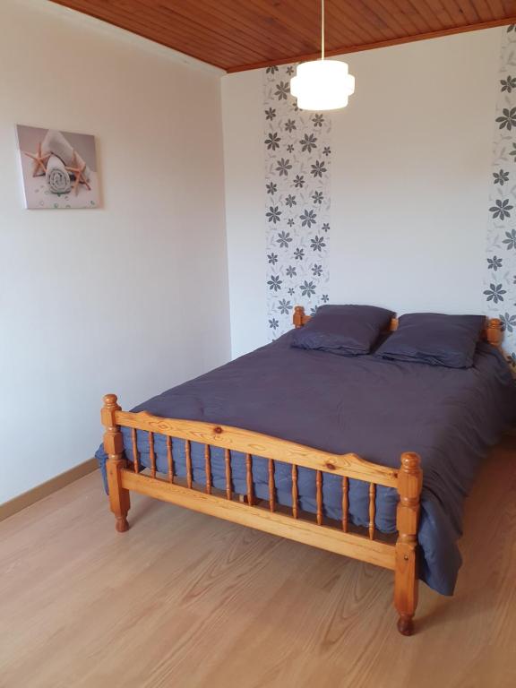a bedroom with a wooden bed with blue pillows at maison 2 chambres au calme in Saint-Bonnet-sur-Gironde