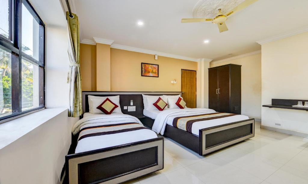 a bedroom with two beds and a window at Hotel Saibala Inn in Chennai