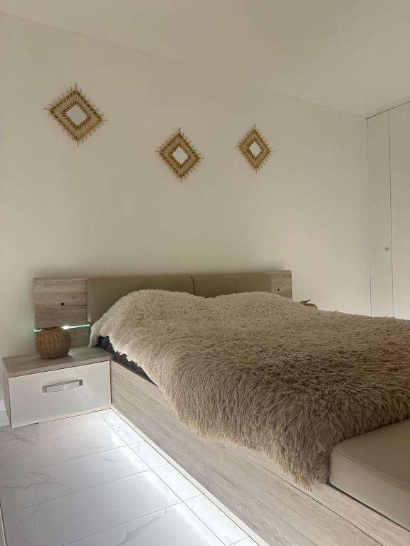 een witte slaapkamer met een bed met een bruine deken bij Appartement moderne avec SPA in Essey-lès-Nancy