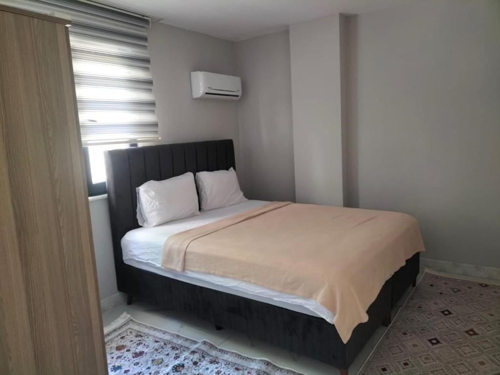 a small bedroom with a bed with white sheets and a window at RÜZGAR APART in Trabzon