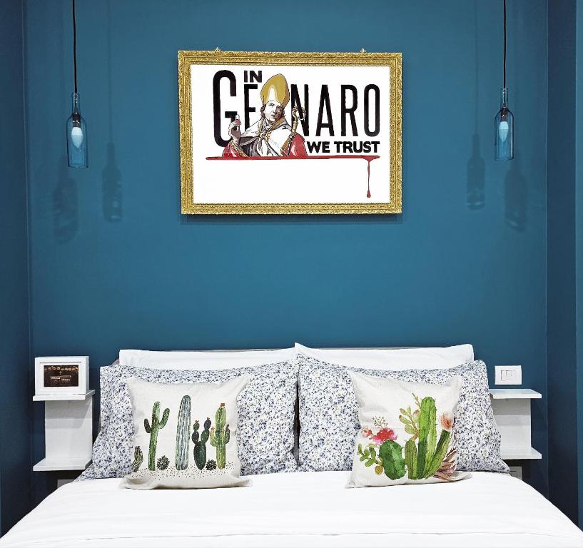 un mur bleu avec une photo au-dessus d'un lit et des oreillers dans l'établissement Napulitano Assaje Home, à Naples