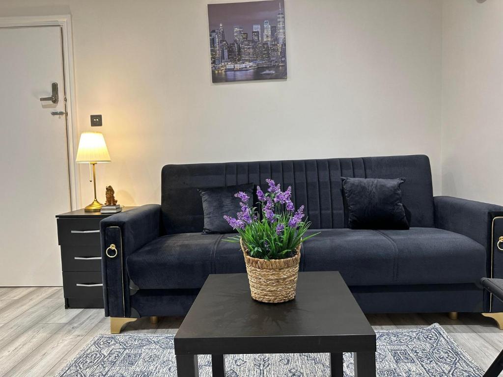 a living room with a couch and a table with purple flowers at Studio flat in London in London