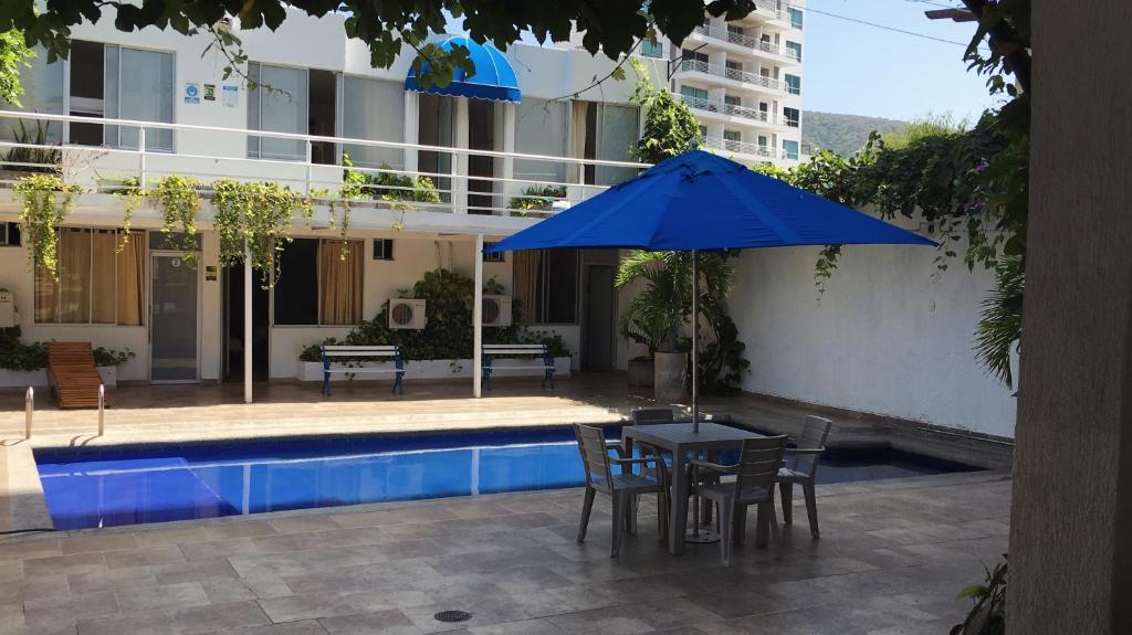 a table with a blue umbrella next to a pool at Hotel Casa Victoria Rodadero in Gaira