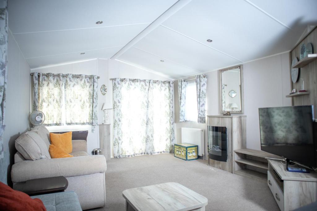 ein Wohnzimmer mit einem Sofa und einem TV in der Unterkunft Sheerness Holiday Caravan for 6 in Sheerness