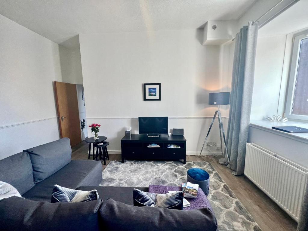Central Apartment Linlithgow في لينليثغو: غرفة معيشة مع أريكة وطاولة