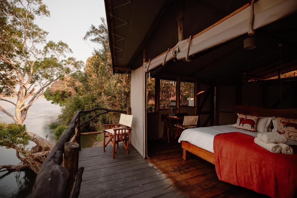 a bedroom with a bed on a wooden deck at Kasabushi Camp in Chunga